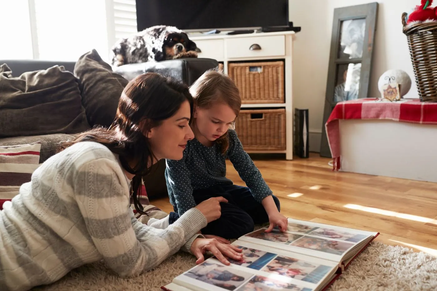 A carer and a young girl looking through a photo album together on the living room floor