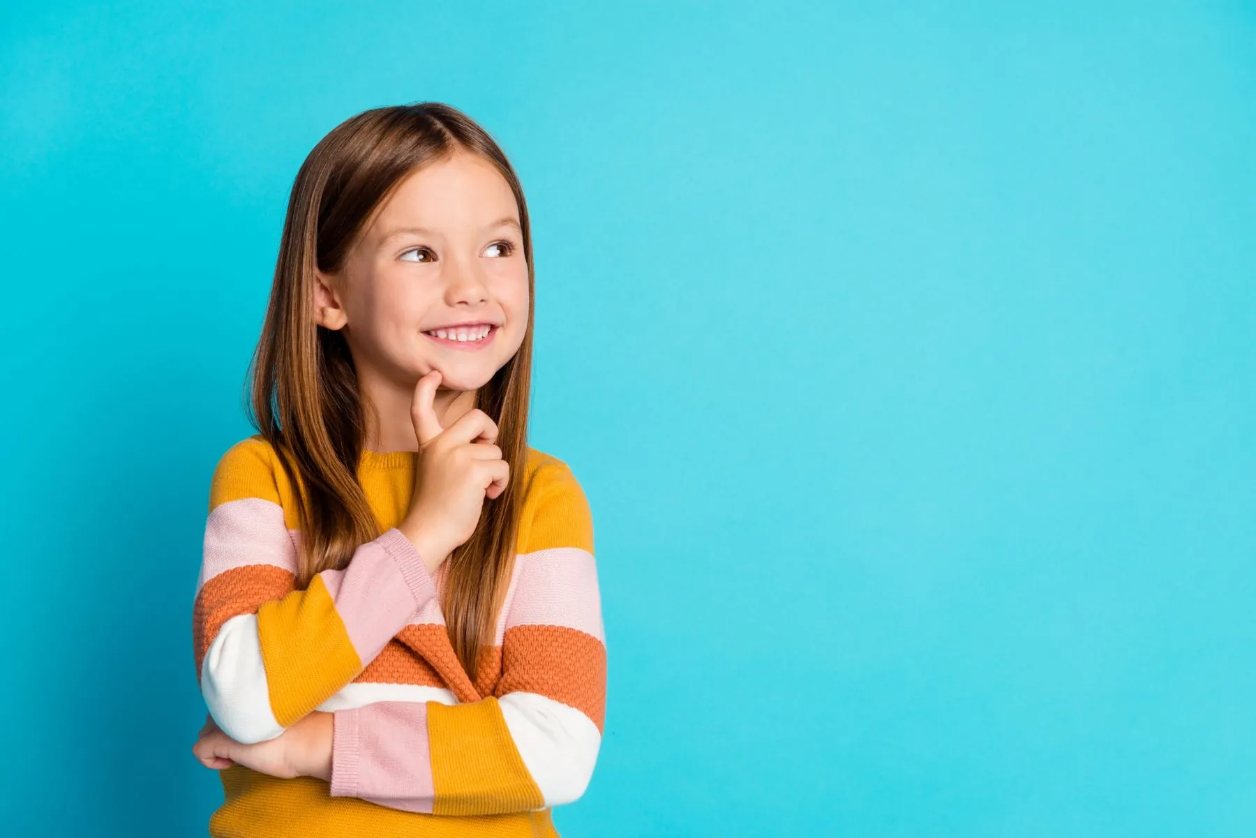A smiling girl with her finger on her chin, thinking