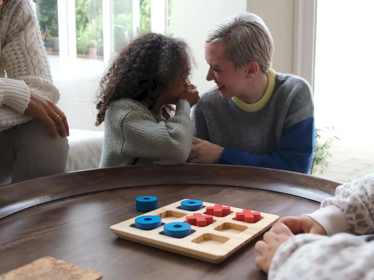 A girl leaning in and laughing with her carer during a game